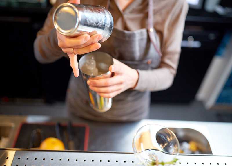 woman-bartender-with-cocktail-shaker-at-bar-PC9JVE4.jpg